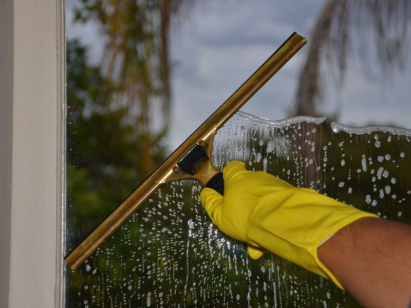 Fensterreinigung mit Abzieher und Handschuh an einer Glasscheibe in Bruchsal